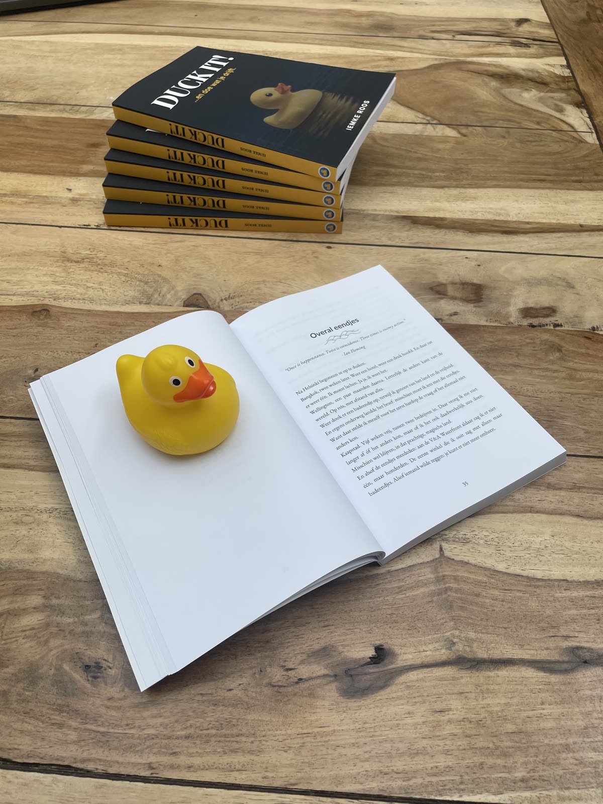 Duck It! opengeslagen op tafel bij het hoofdstuk Overal eendjes, met de badeend op de linkerpagina en een stapel boeken erachter