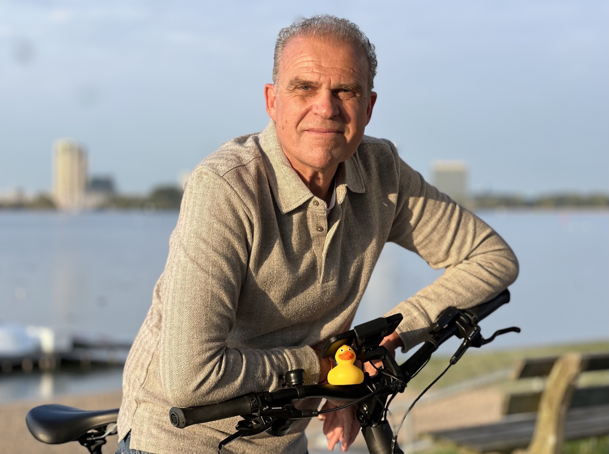 Iemke Roos bij het water, leunend op zijn fiets met de badeend op het stuur