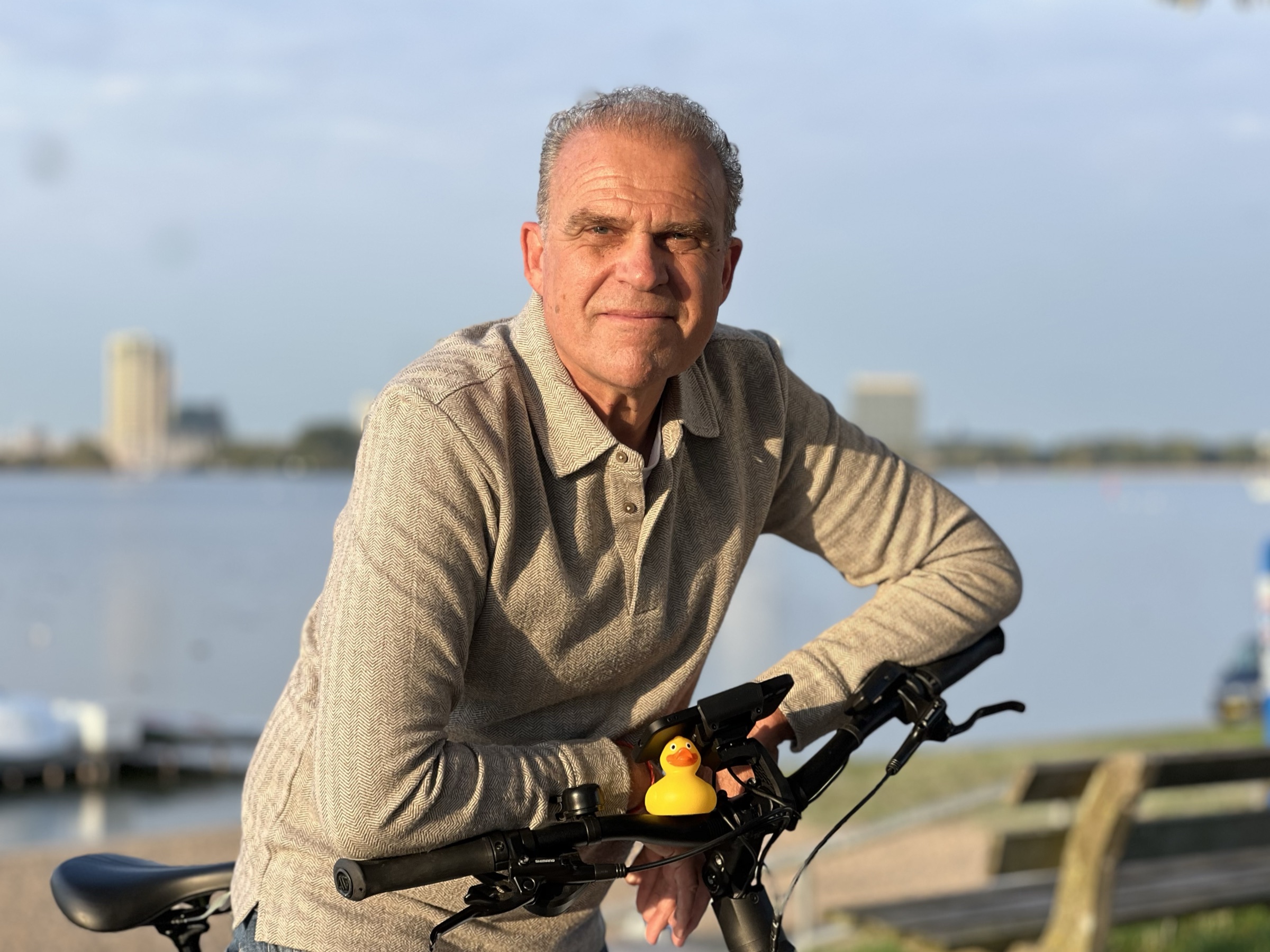 Iemke Roos bij zijn fiets aan het water, met de badeend op het stuur